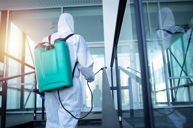 Man with tank reservoir on his back spraying disinfectant to stop corona virus