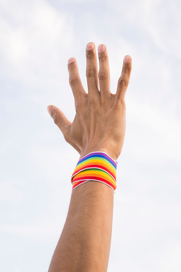 Free Photo man with tape in lgbt colors on hand and blue sky