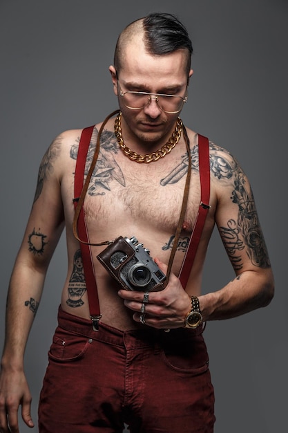 Man with tattoos on his body holding photo camera. isolated on grey.