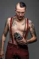 Free photo man with tattoos on his body holding photo camera. isolated on grey.