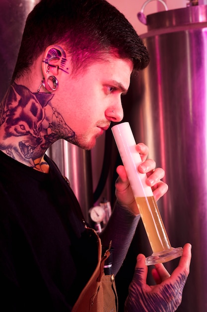 Foto gratuita uomo con tatuaggi che producono birra artigianale