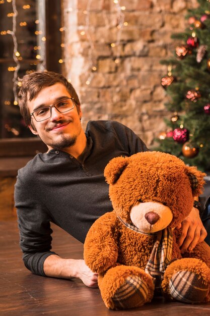 Man with teddy in front of christmas tree