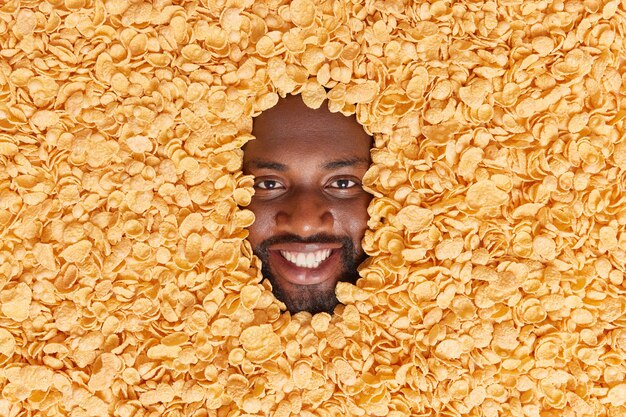  man with thick beard buried in dry cornflakes smiles pleasantly going to prepare traditional breakfast eats healthy food has delicious snack