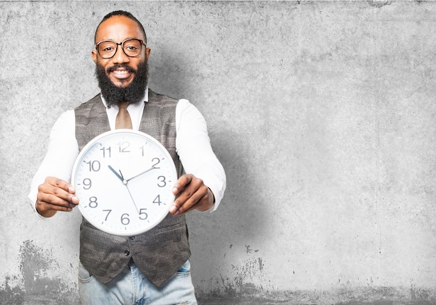 Man with tie smiling and holding a clock