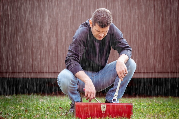 Free photo man with a toolbox under the rain