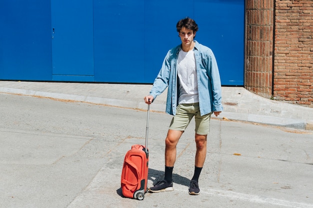 Man with travelling suitcase posing on street