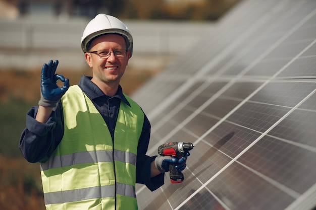 Foto gratuita uomo con casco bianco vicino a un pannello solare