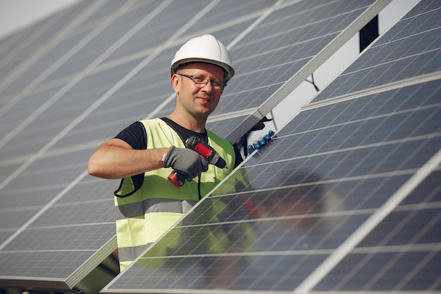 Foto gratuita uomo con casco bianco vicino a un pannello solare