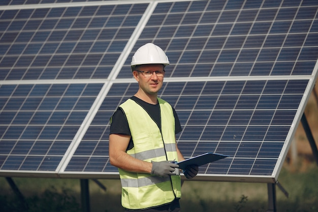 Man with white helmet near a solar panel