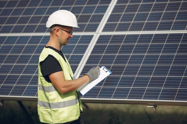 Foto gratuita uomo con casco bianco vicino a un pannello solare