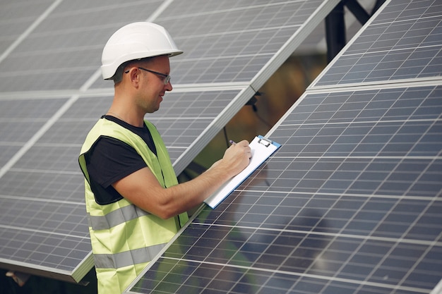 Foto gratuita uomo con casco bianco vicino a un pannello solare