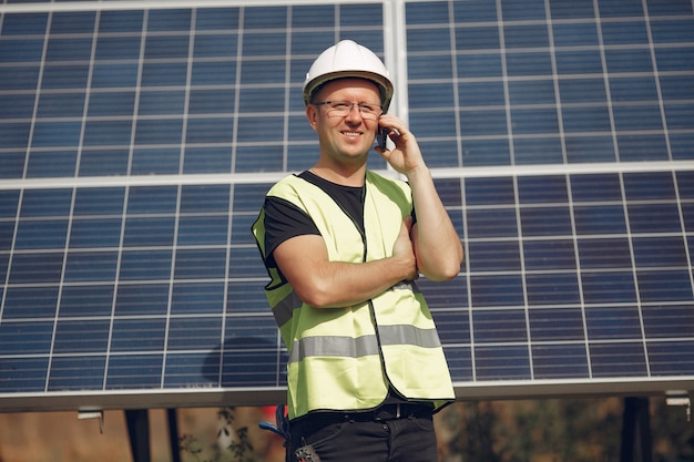 Foto gratuita uomo con casco bianco vicino a un pannello solare