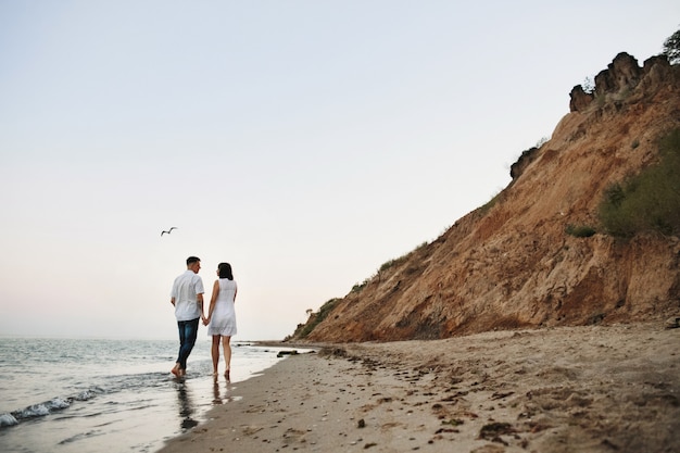 Man with woman are walking along the sea