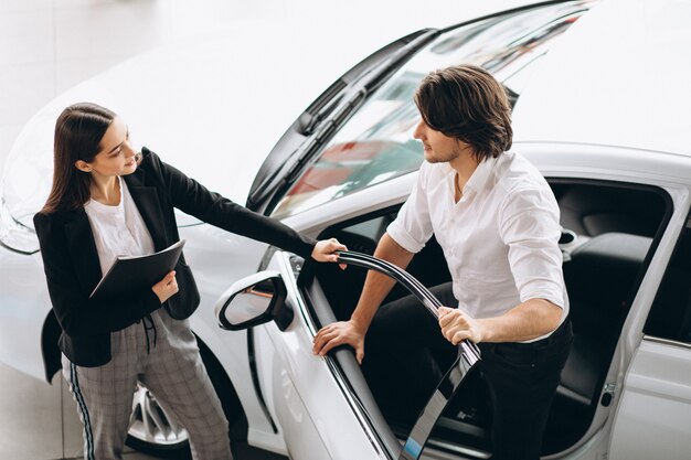 Man with woman in a car showroom choosing a car