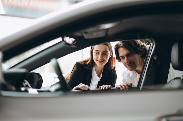 車のショールームで車を選ぶ女性を持つ男