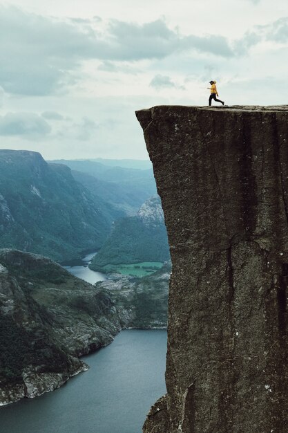 黄色のジャケットを持つ男が岩の上にポーズをとる