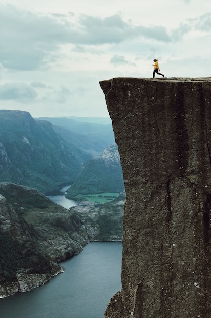 Man with a yellow jacket poses on the top of the rock