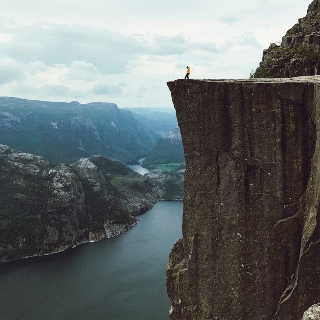 Man with a yellow jacket poses on the top of the rock