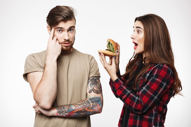 Man , woman annoying guy, playing with burger.