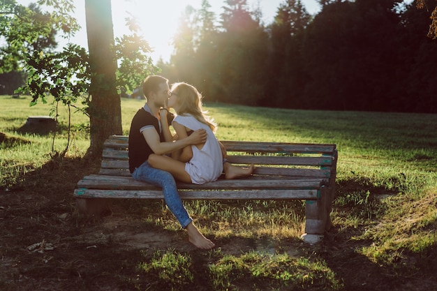 мужчина и женщина сидят на скамейке и целуются
