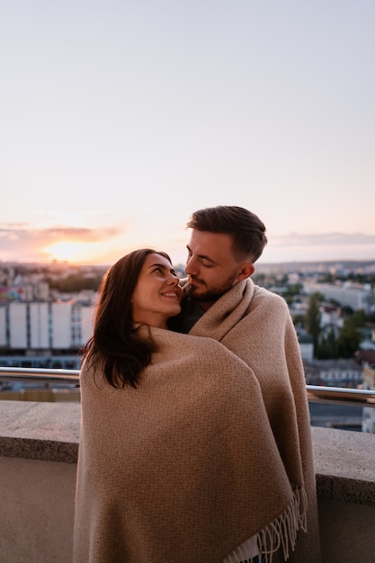 Uomo e donna sul balcone al tramonto in città