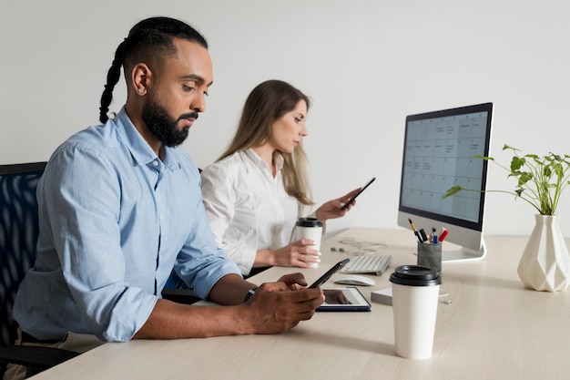 L'uomo e la donna sono dipendenti dai loro telefoni anche al lavoro