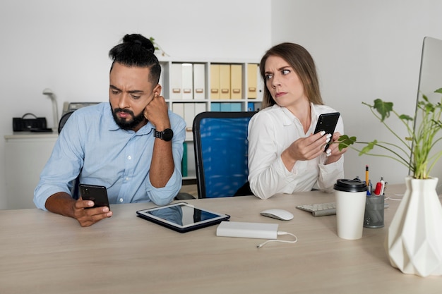 男性と女性が自分の携帯電話にはまっている