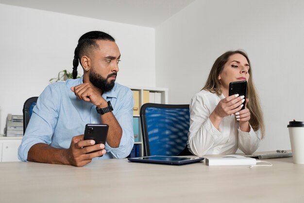 男性と女性が自分の携帯電話にはまっている