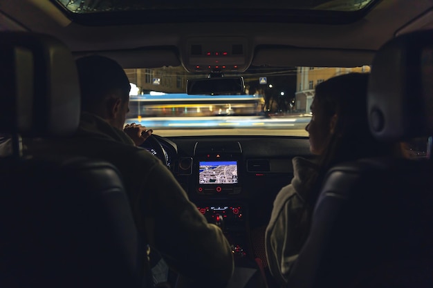 Uomo e donna in un'auto di notte vista dall'auto