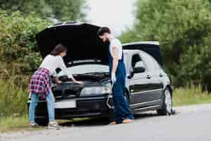 Free photo man and woman checking car engine