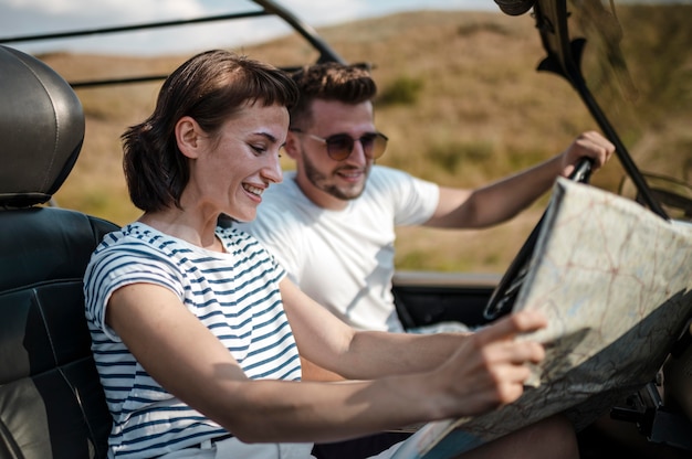 Man and woman checking map while traveling by car