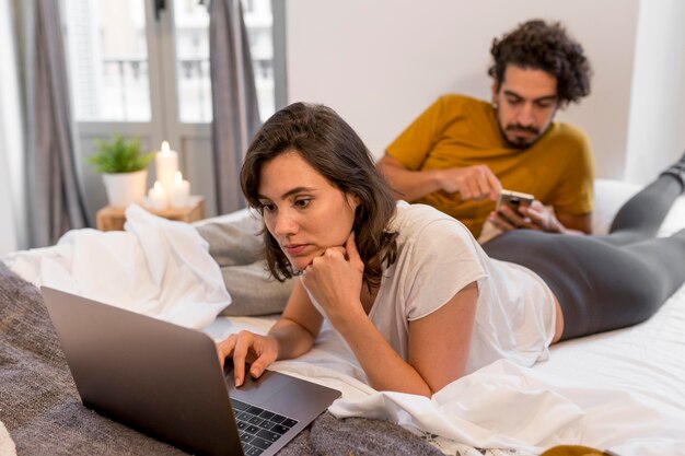 Мужчина и женщина проверяют свои устройства дома