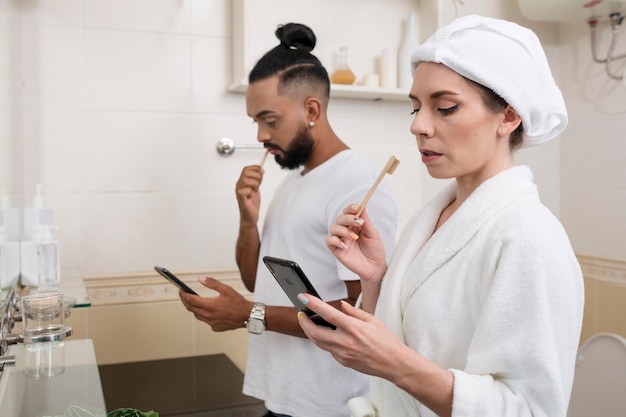 Мужчина и женщина проверяют свои телефоны даже в ванной