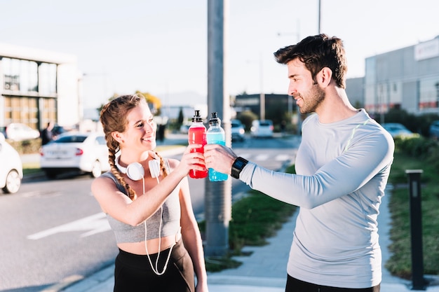 Man and woman clinking water bottles