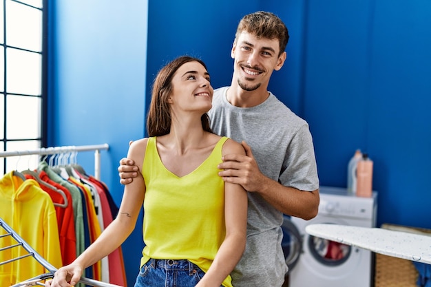 Free photo man and woman couple hugging each other hanging clohes on clothesline at laundry room