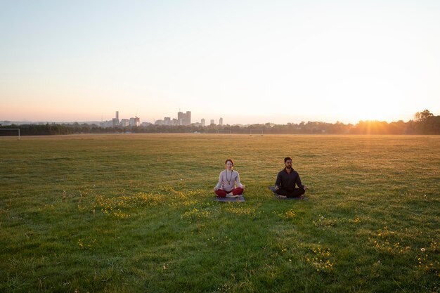 Man and woman doing yoga together outdoors