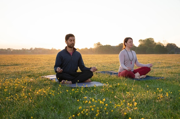 Man and woman doing yoga together outdoors