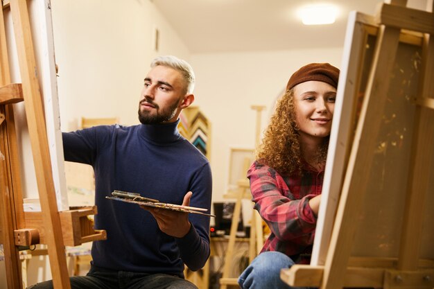 Man and woman draw paintings on easels