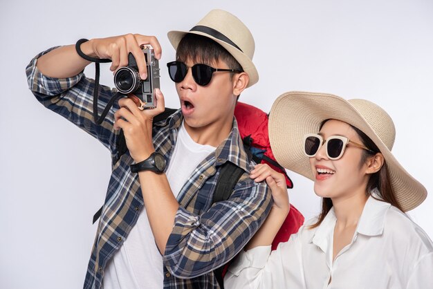 Man and woman dressed to travel, wear glasses, and take pictures