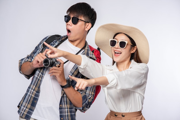 Man and woman dressed to travel, wear glasses, and take pictures