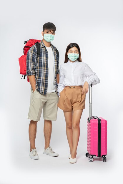 남자와 여자는 여행을 위해 옷을 입고, 수하물과 함께 마스크를 쓰고