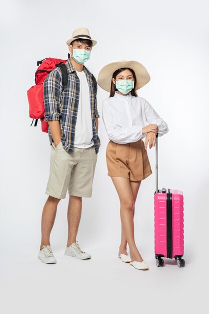 남자와 여자는 여행을 위해 옷을 입고, 수하물과 함께 마스크를 쓰고