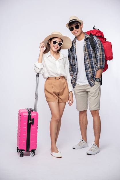 Man and woman dressed up wearing glasses to travel with suitcases