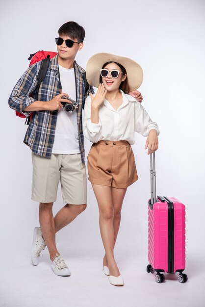 男と女はスーツケースを持って旅行するために眼鏡をかけてドレスアップ