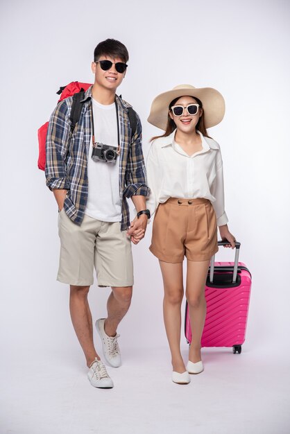 Man and woman dressed up wearing glasses to travel with suitcases