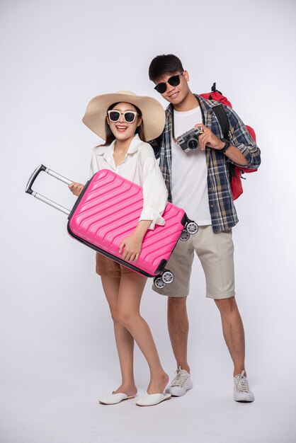 Мужчина и женщина, одетые в очки, путешествуют с чемоданами