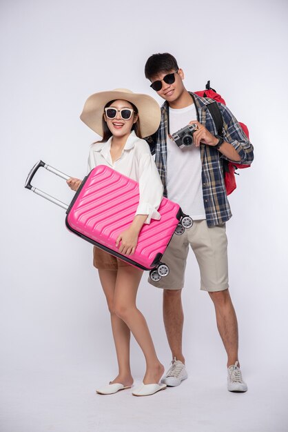 Man and woman dressed up wearing glasses to travel with suitcases