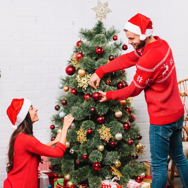男性と女性がクリスマスツリーをドレッシング