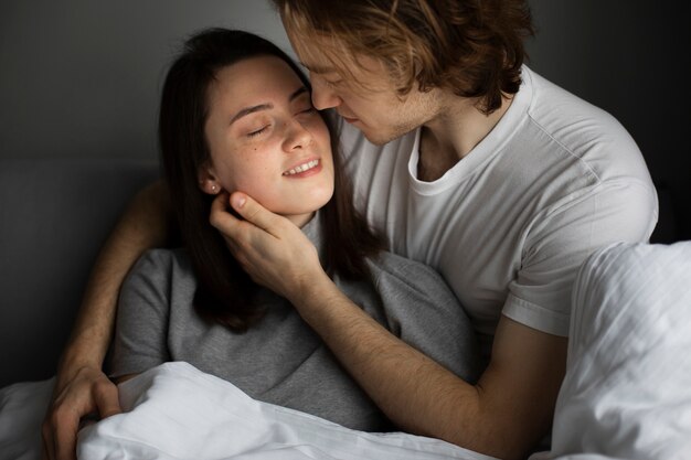 Мужчина и женщина обнимаются, улыбаясь в постели