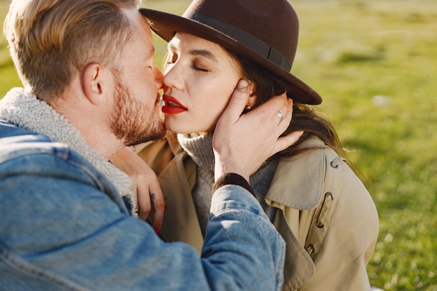 Man and woman in fashion clothes sitting on a nature on a picnic rug. Man wearing jacket and woman coat